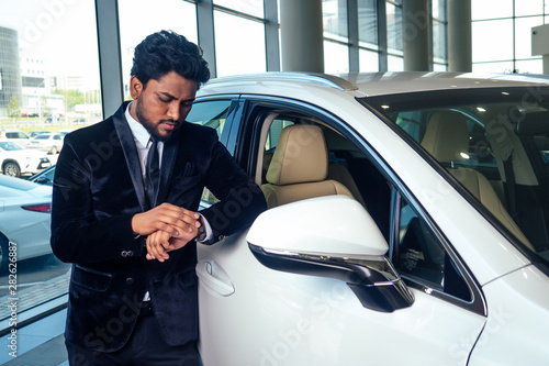 happy business indian man in well-dressed black suit buy new biodiesel eco automobile in lux showroom © yurakrasil