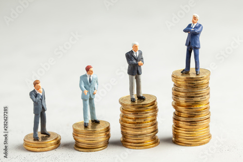 Successful businessman with big profits at the top of the stairs by coins and less successful businessmen with small companies. Adequate investment in the company.