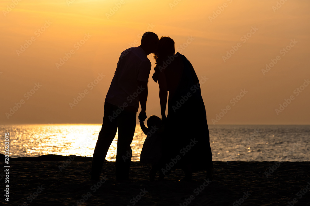silhouette of a family with a child by the sea at sunset