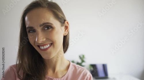 Portrait of young businesswoman smiling and turning head toward camera while in modern office