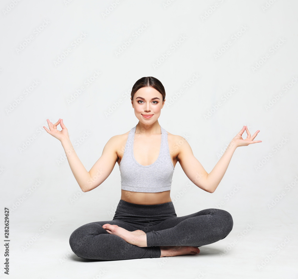 Portrait of attractive woman doing yoga, pilates over light grey background. Healthy lifestyle and sports concept. Portrait of attractive woman doing yoga, pilates over light grey background. Healthy lifestyle and sports concept.