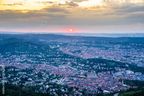 Germany, Orange sky sunset in summertime over city stuttgart, aerial view above houses, roofs and buildings in the evening