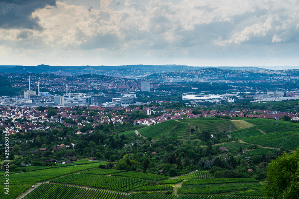 Germany, Aerial view above green vineyards next to houses and arena of stuttgart city in basin surrounded by nature landscape