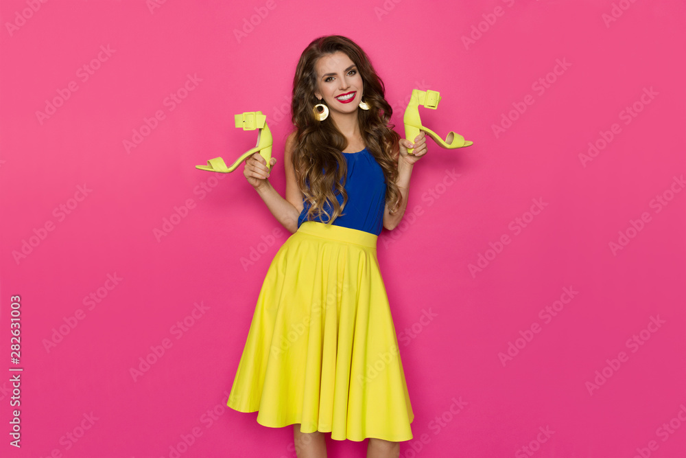 Vibrant Young Woman Is Holding Yellow High Heels Shoes And Smiling Vibrant Young Woman Is Holding Yellow High Heels Shoes And Smiling