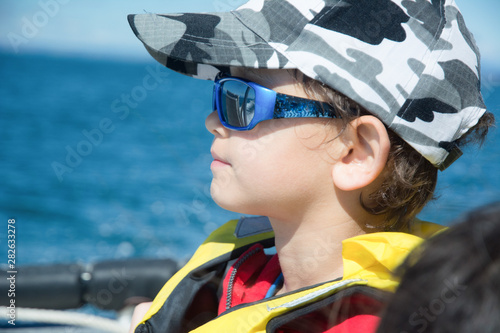 Young boy in a life vest with an ocean in the background