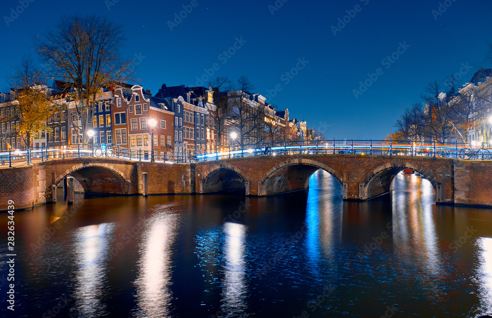 Architecture and canals with bridges at night in Amsterdam.