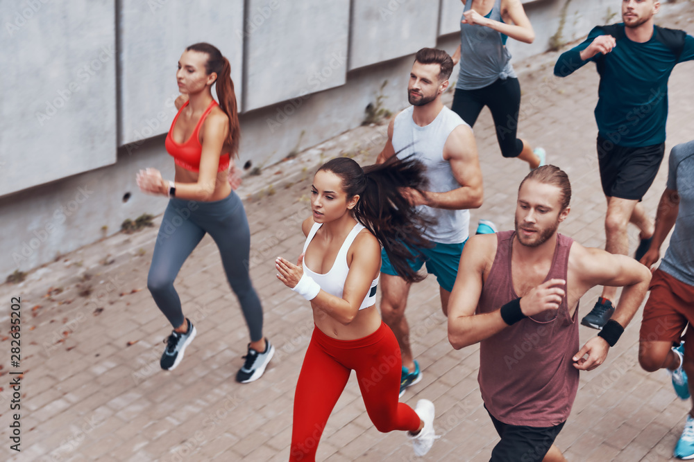 Fototapeta premium Top view of young people in sports clothing jogging while exercising outdoors