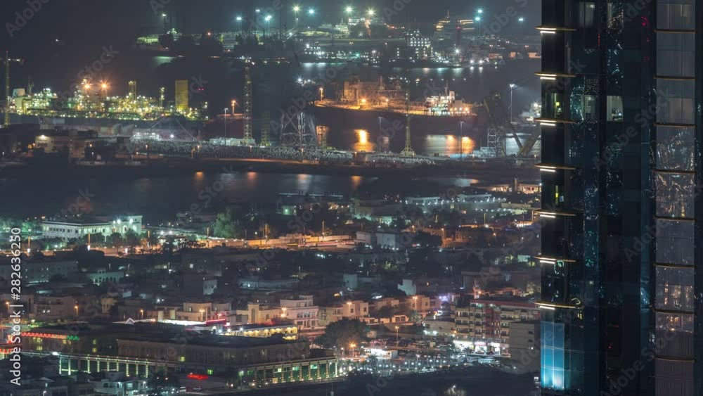 Aerial view from Downtown of Dubai night timelapse with skyscrapers, houses and port Rashid on a background, ships docking at sea port, UAE Aerial view from Downtown of Dubai night timelapse with skyscrapers, houses and port Rashid on a background, ships docking at sea port, UAE