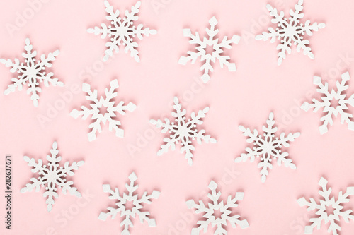 Christmas background. White snow decorations on a pink background.
