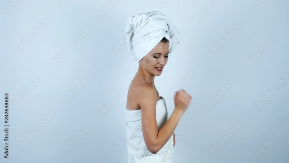 young beautiful woman with white towel on her head and over her body dancing with her arms up feeling happy on isolated white background young beautiful woman with white towel on her head and over her body dancing with her arms up feeling happy on isolated white background