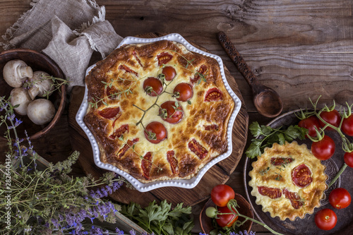 Kish pie with tomatoes and mushrooms, cream cheese on wooden background