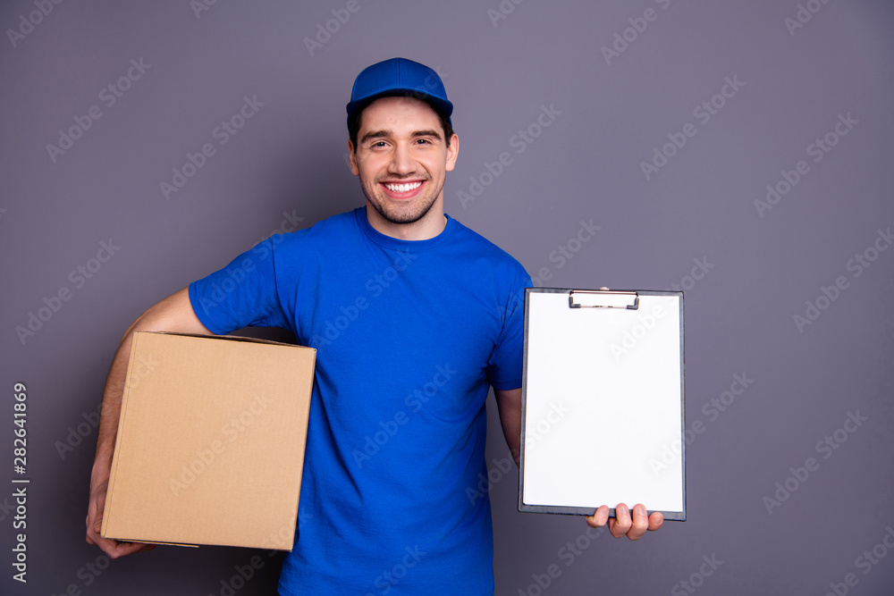 Close up photo express speed specialist he him his delivery boy hold strong arms large big parcel box accept clipboard check recipient wear blue t-shirt cap corporate suit isolated grey background Close up photo express speed specialist he him his delivery boy hold strong arms large big parcel box accept clipboard check recipient wear blue t-shirt cap corporate suit isolated grey background