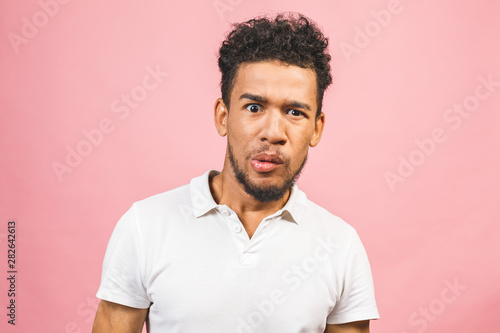 A young amazed shocked funny African American male isolated against pink background.