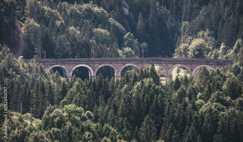 Train running on the viaduct of historic old beautiful Semmering railway Semmeringbahn in alps mountains on an summer day, Austria