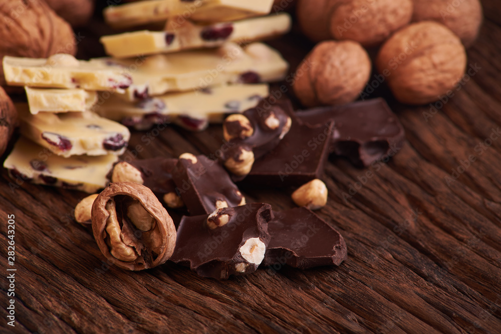 Nuts and milk and dark chocolate pieces on wooden background Nuts and milk and dark chocolate pieces on wooden background