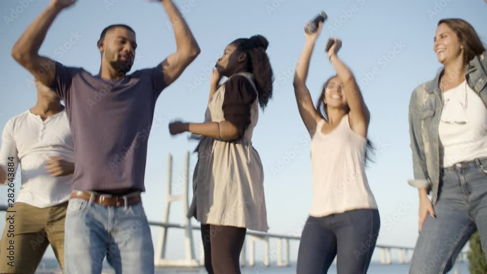 Happy smiling friends dancing and jumping in park. Young people listening music and relaxing together. Leisure concept Happy smiling friends dancing and jumping in park. Young people listening music and relaxing together. Leisure concept