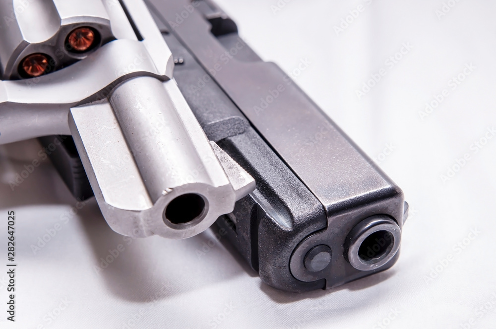 Two handguns, a silver snub nosed 357 magnum revolver and a black 9mm pistol on a white background