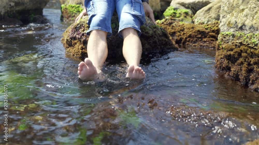 Men's feet are washed by sea waves. The barefoot of the guy stands on a stone coast. Kicking with seawater and floating seaweed 4k Men's feet are washed by sea waves. The barefoot of the guy stands on a stone coast. Kicking with seawater and floating seaweed 4k