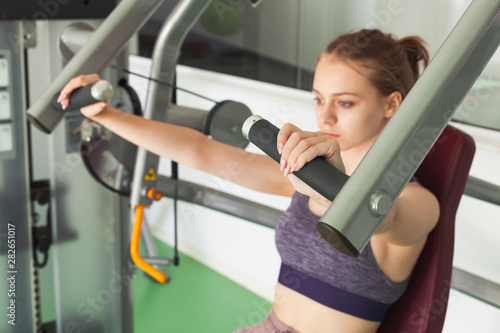 Girl does machine chest press exercising