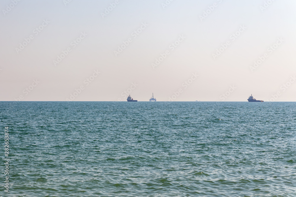 Sea horizon with ships and drilling platform