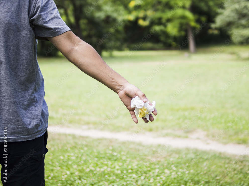 Close-up of man hand throwing crumpled paper in park Close-up of man hand throwing crumpled paper in park