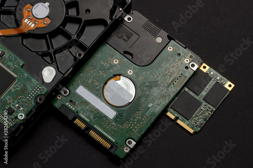Three kinds of hard drives on black background. From old to new. Top view, flat lay