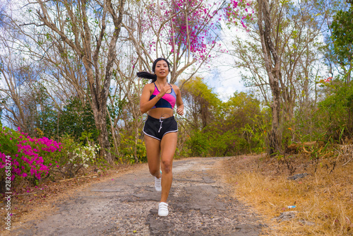 young attractive and exotic Asian Indonesian runner woman in jogging workout outdoors at countryside road track nature running sweaty pushing hard © TheVisualsYouNeed