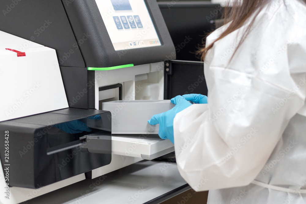 Med lab technologist using DNA sequencing equipment in science room. Chemist or scientist wearing blue medical glove working in hospital or university research laboratory. Med lab technologist using DNA sequencing equipment in science room. Chemist or scientist wearing blue medical glove working in hospital or university research laboratory.