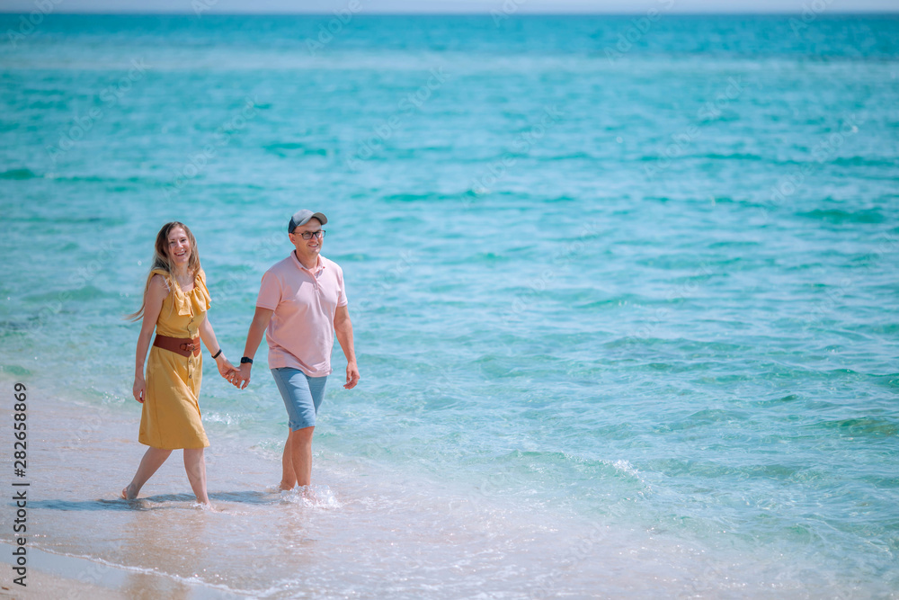 Loving couple walks along the shore of the sea beach.