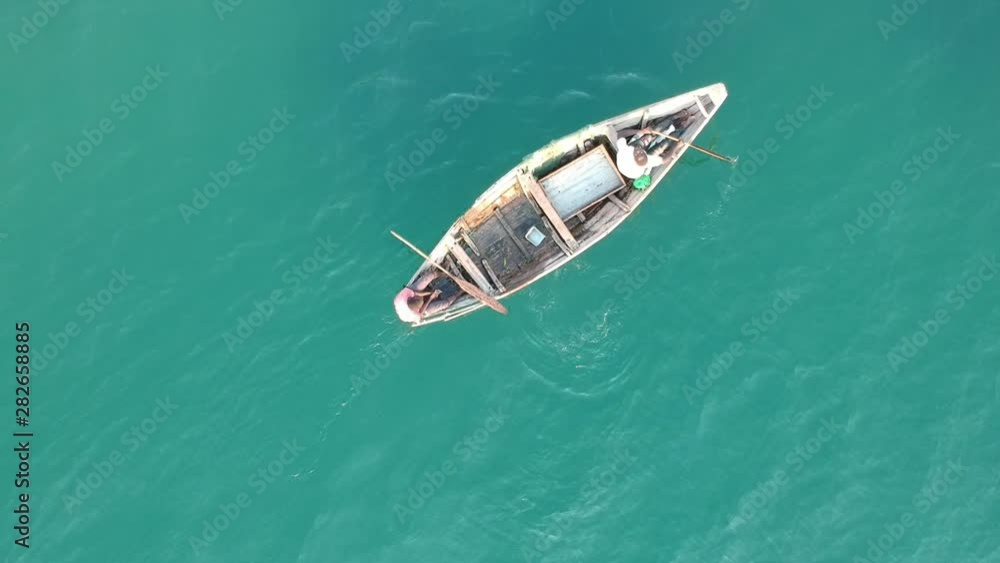 Two black men on wooden boat on light blue lake Two black men on wooden boat on light blue lake