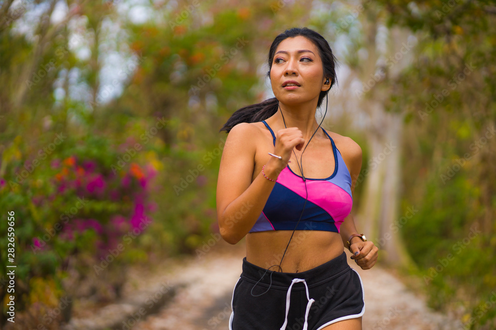 young attractive and exotic Asian Indonesian runner woman in jogging workout outdoors at countryside road track nature running sweaty pushing hard young attractive and exotic Asian Indonesian runner woman in jogging workout outdoors at countryside road track nature running sweaty pushing hard