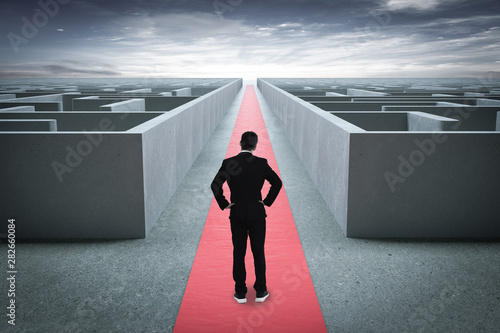 Businessman going straight ahead on a wide road between mazes photo