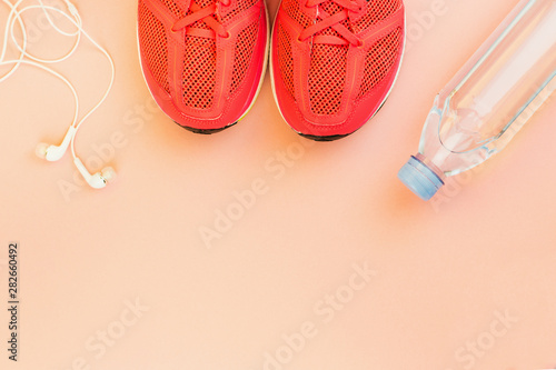 White headphones, a bottle of fresh water and pink sneakers