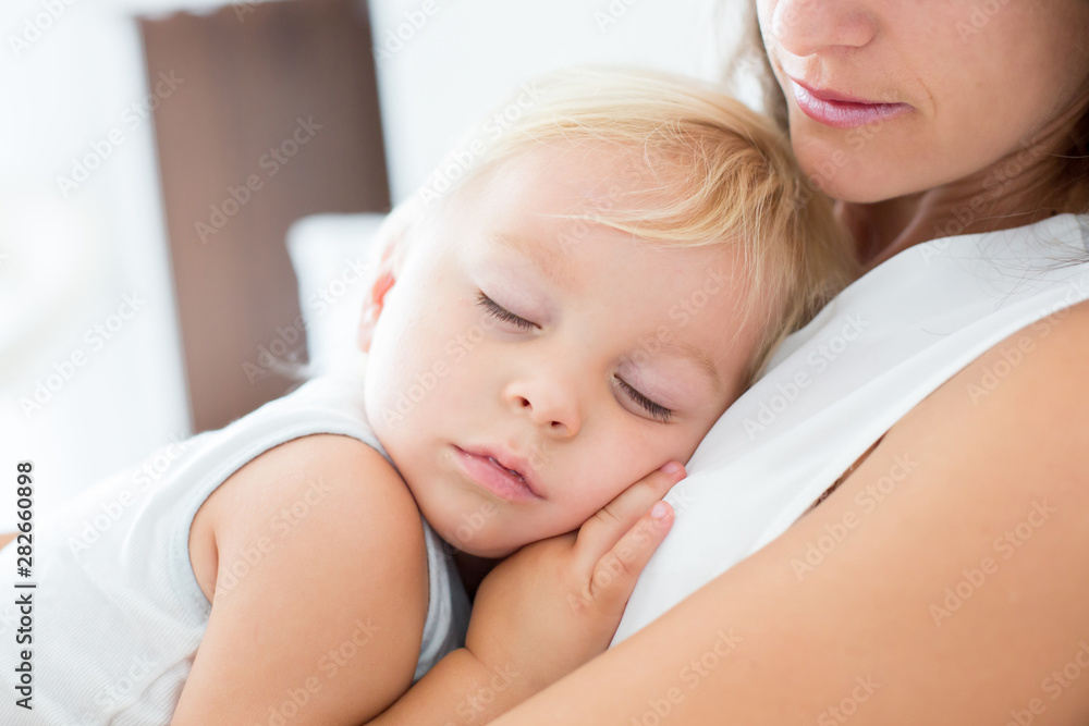 Young mother lying in bed with her sleeping toddler baby boy Young mother lying in bed with her sleeping toddler baby boy