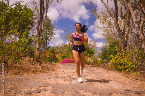 young attractive and exotic Asian Indonesian runner woman in jogging workout outdoors at countryside road track nature running sweaty pushing hard