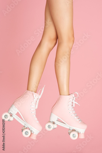 Legs up! Roller skates on slim leg isolated on the colorful background.