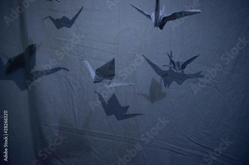 grullas de papel en fondo blanco y azul con sombras 