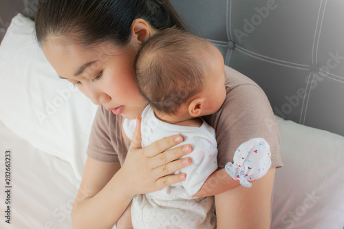 Beautiful mother holding her lovely baby . Infant resting on the shoulder to burp,