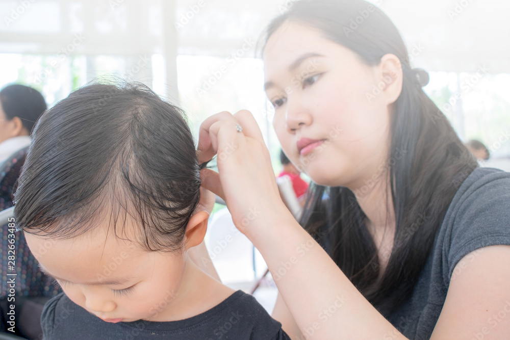 My daughter. Beautiful happy mother smiling and making a hairdo for her little daughter while standing behind her child My daughter. Beautiful happy mother smiling and making a hairdo for her little daughter while standing behind her child