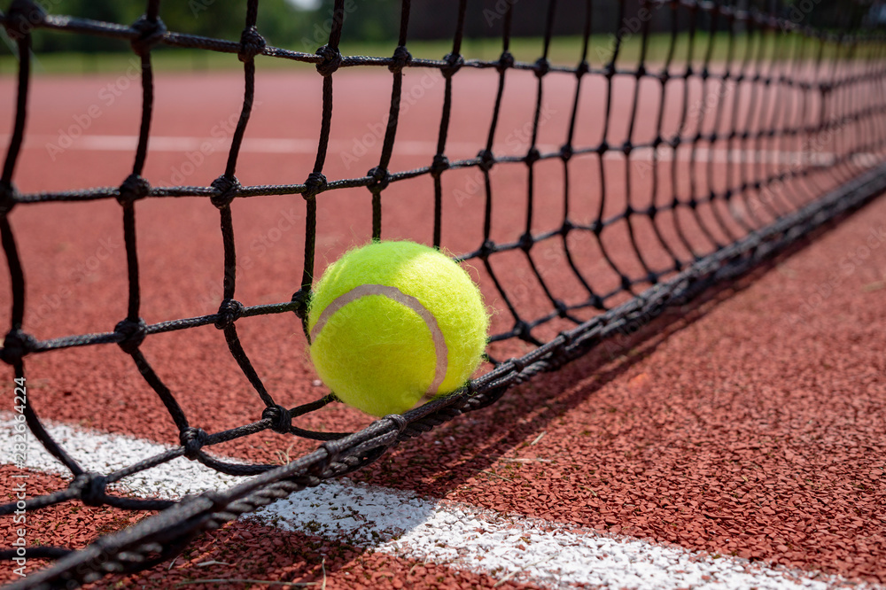 Detail of single tennis ball on black net