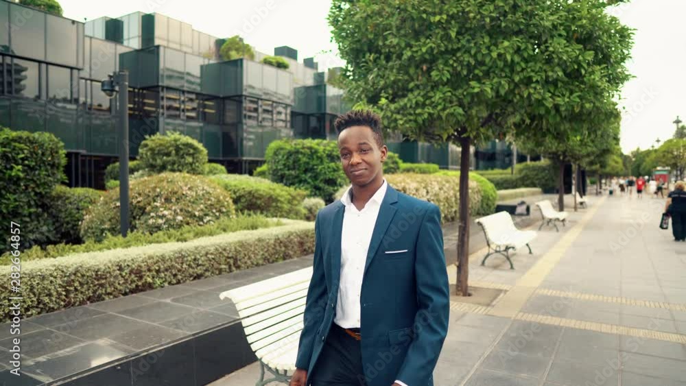 African American businessman wearing blue suit walking near office. Business concept African American businessman wearing blue suit walking near office. Business concept