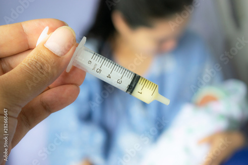 Mother feeding newborn baby milk with syringe