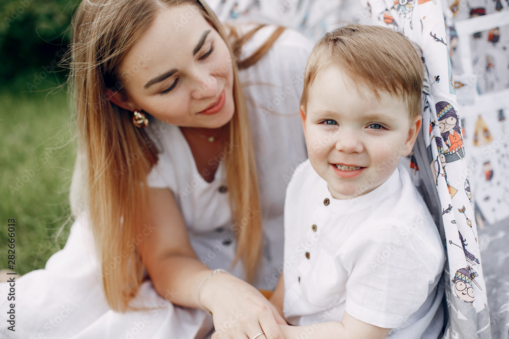 Family in a summer park. Mother in a white dress. Cute little boy Family in a summer park. Mother in a white dress. Cute little boy