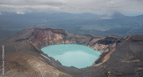 Karymsky Lake, a crater pool located in the Karymsky volcano on the Kamchatka Peninsula, Russia. Radius 5 km. Toxic gases turned this into the large acid lakes. Aquamarine blue poisonous basin.