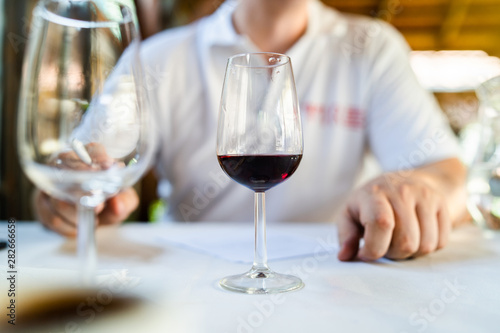 Close up on glass of red wine on the table in front of the sommelier expert at the wine testing degustation event © Miljan Živković
