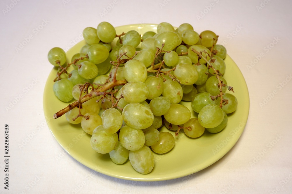 Bunch of green grapes on light green plate