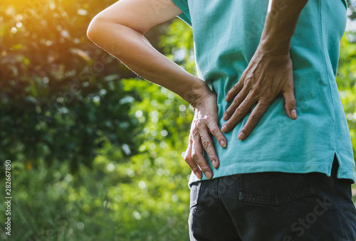 Closeup hands of woman touching her back pain in healthy concept on nature background. photo