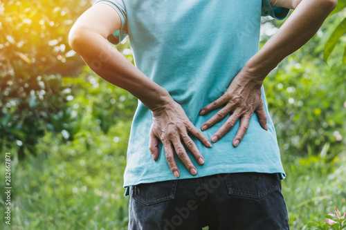 Closeup hands of woman touching her back pain in healthy concept on nature background.
