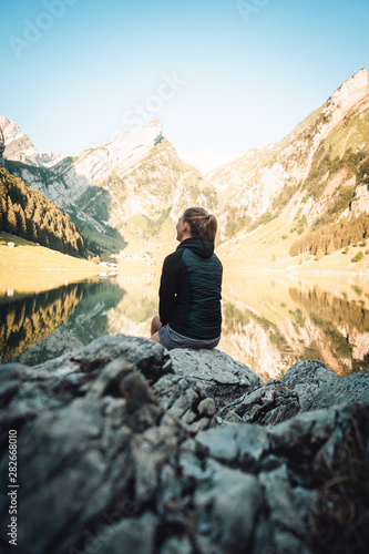 woman sitting at mountain lake