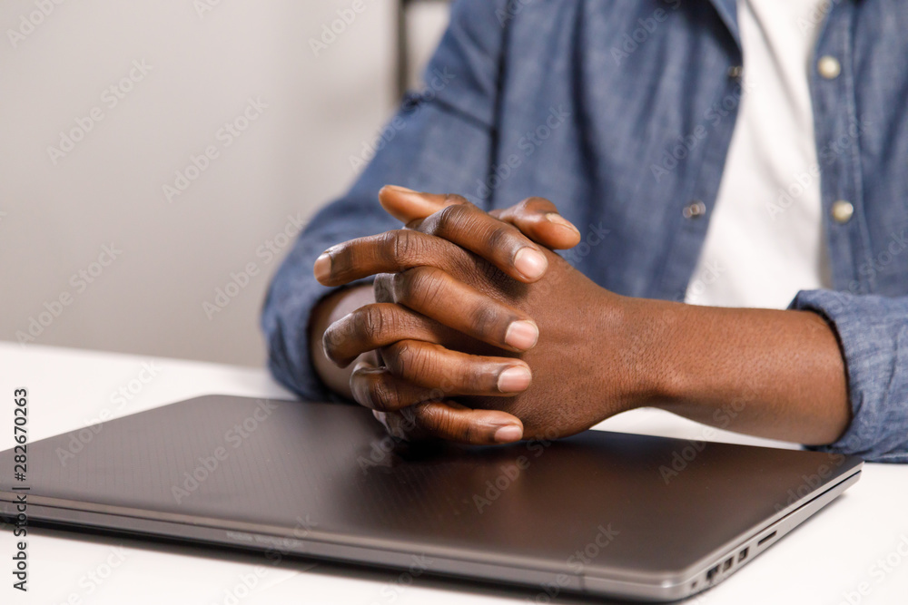 Fototapeta premium Close up view of african man sitting at the table with closed laptop